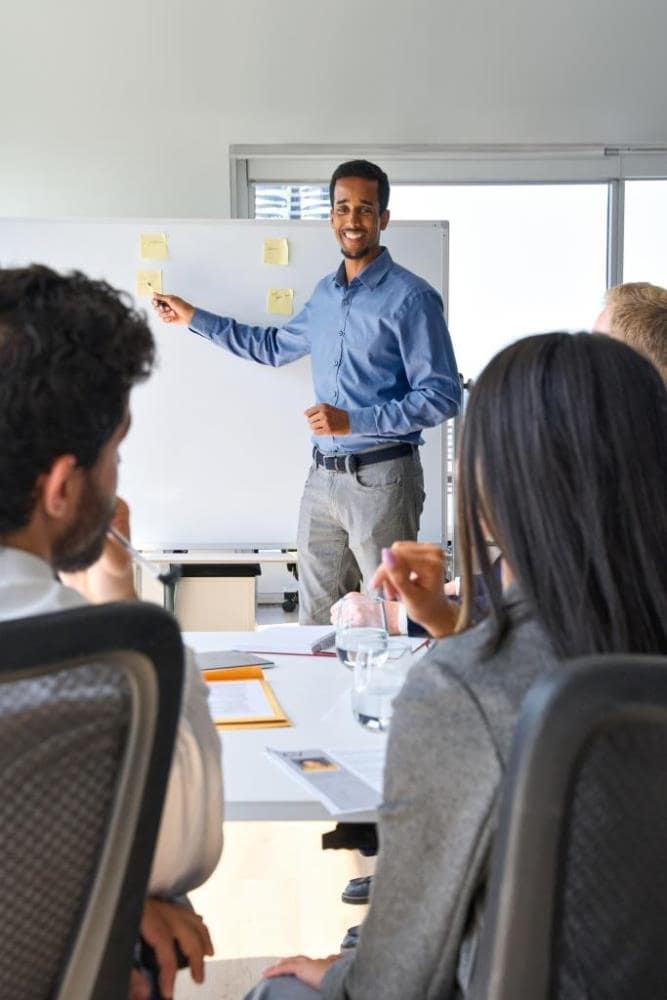 African business man presenter team leader giving presentation training on whiteboard in office. Company executive manager presenting corporate strategy at group conference workshop meeting